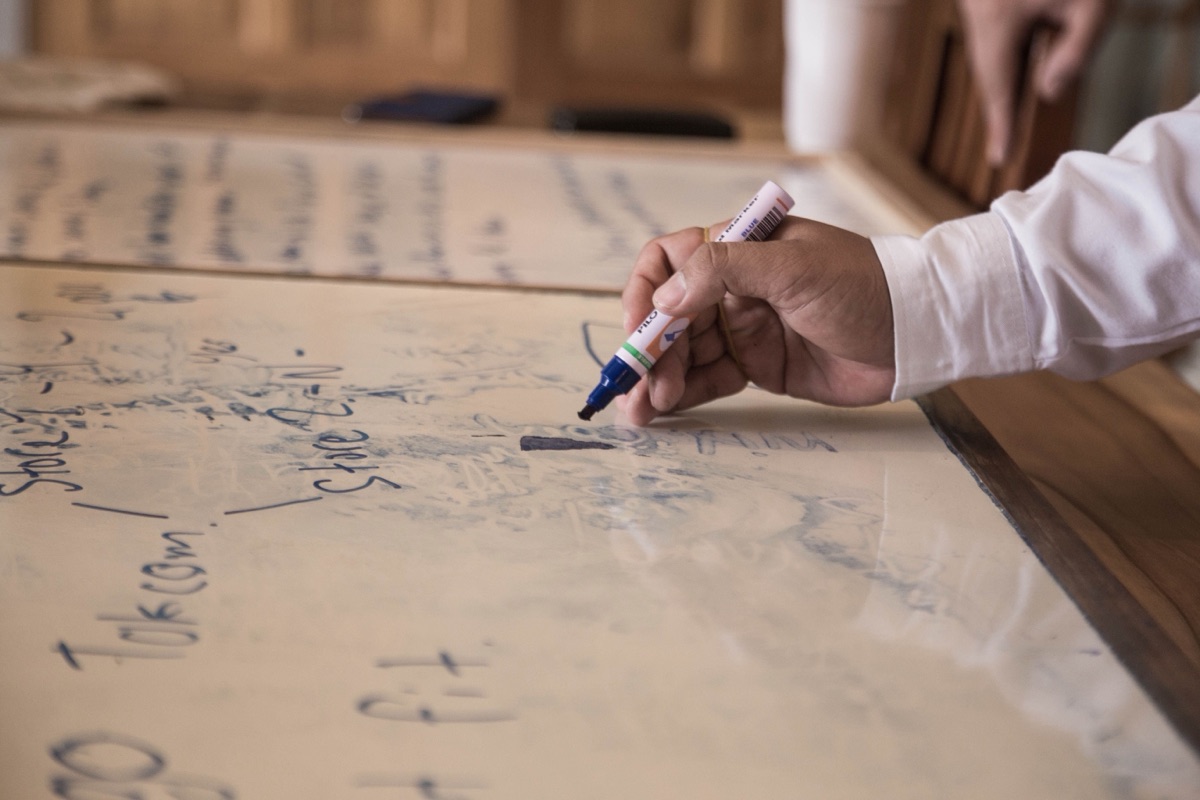 Hand writing on a whiteboard during a working session